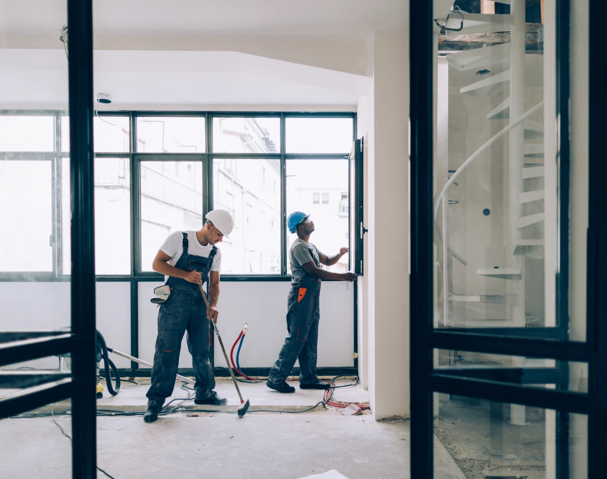Two workers in hard hats fixing room