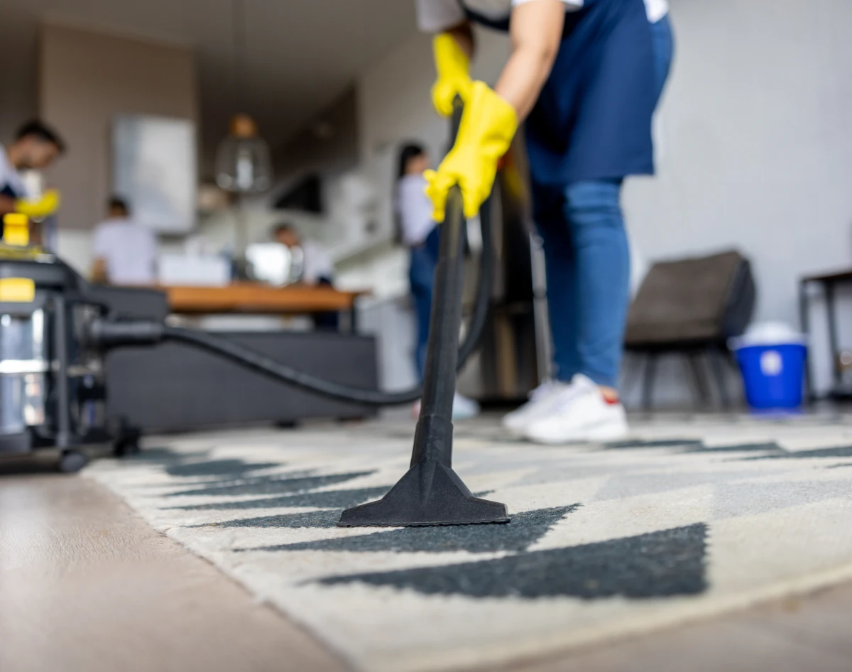Housekeeper using vacuum on geometric rug