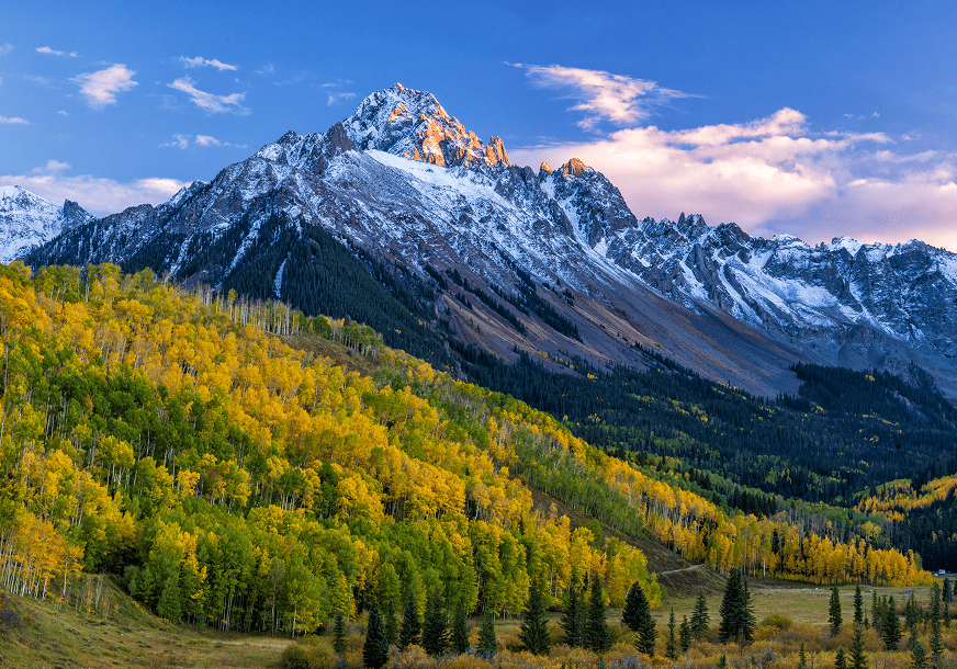 Snow-capped mountain with colorful autumn forest.